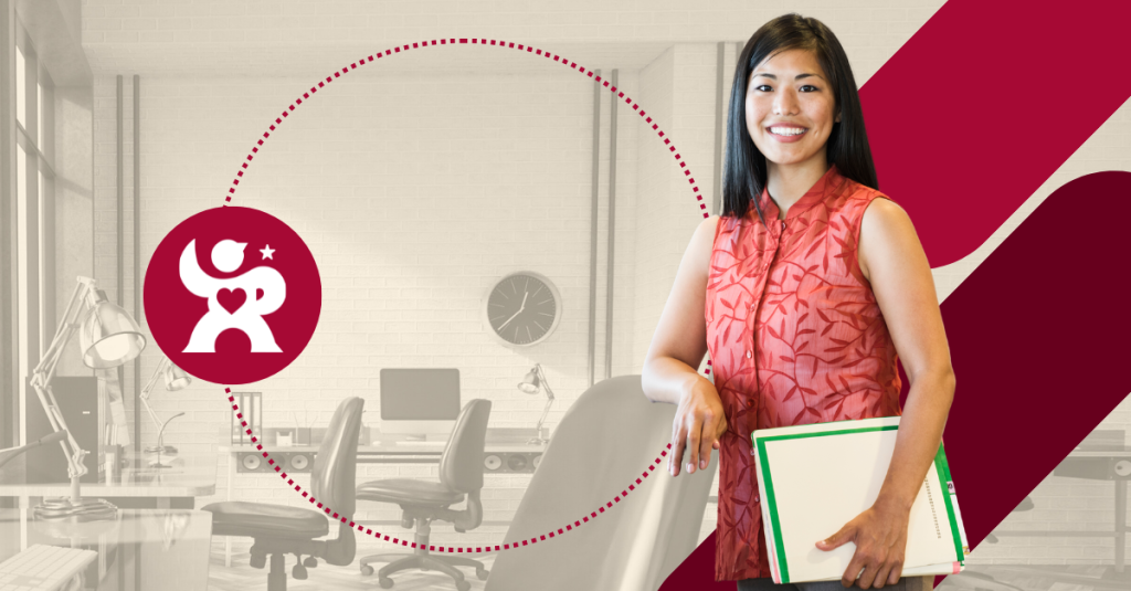 A woman standing in an office holding a folder.