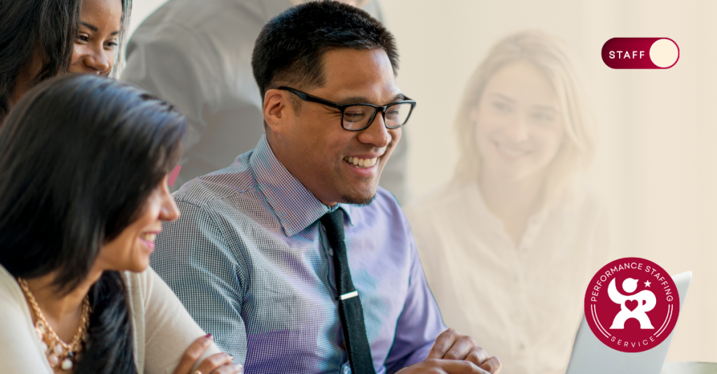 A group of people sitting around a laptop computer.