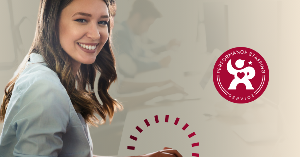 A woman is smiling and working on a laptop.